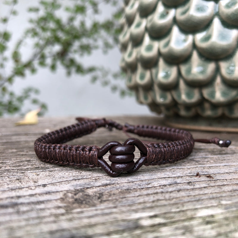 Macrame Ancla Leather Men's Bracelet in chocolate brown, is handwoven from sustainably sourced leather with a sliding clasp and adjustable macrame knot. It has a leather knot in the center and framed by woven band on both sides.