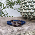 The navy blue and brown Macrame Playa Leather Men's Bracelets are handwoven, made with sturdy waxed cotton that is wrapped around a double leather intertwined cord, and closed with an Italian waxed-cord clasp. This bracelet has a large knot in the center.
