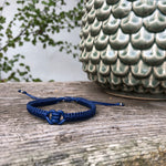Macrame Ancla Leather Men's Bracelet in navy blue, is handwoven from sustainably sourced leather with a sliding clasp and adjustable macrame knot. It has a leather knot in the center and framed by woven band on both sides.