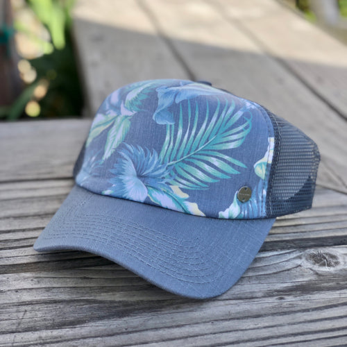 The Gidget trucker cap, by Kooringal has a mesh back, blue brim, and a blue and green tropical palm print.