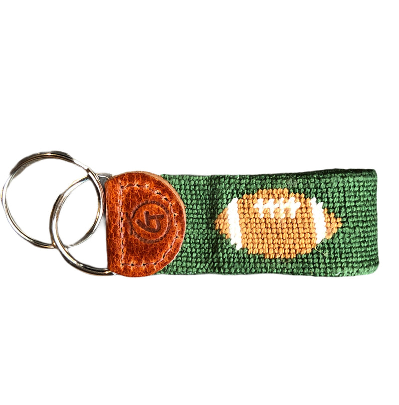 Needlepoint and leather keychain with football on a green background.