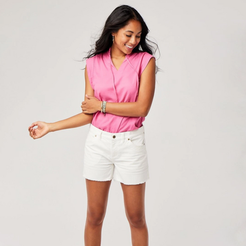 Front view of female model wearing Carve Designs Oahu shorts in cloud (white). Shorts are corduroy with 4" inseam and raw hem bottom. Paired with pink top.