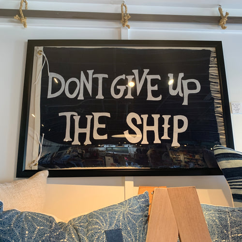 Large framed flag with dark navy background and capitalized ivory letters that spell DON'T GIVE UP THE SHIP. 
