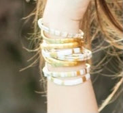 close up of assorted bracelets with white and gold beads