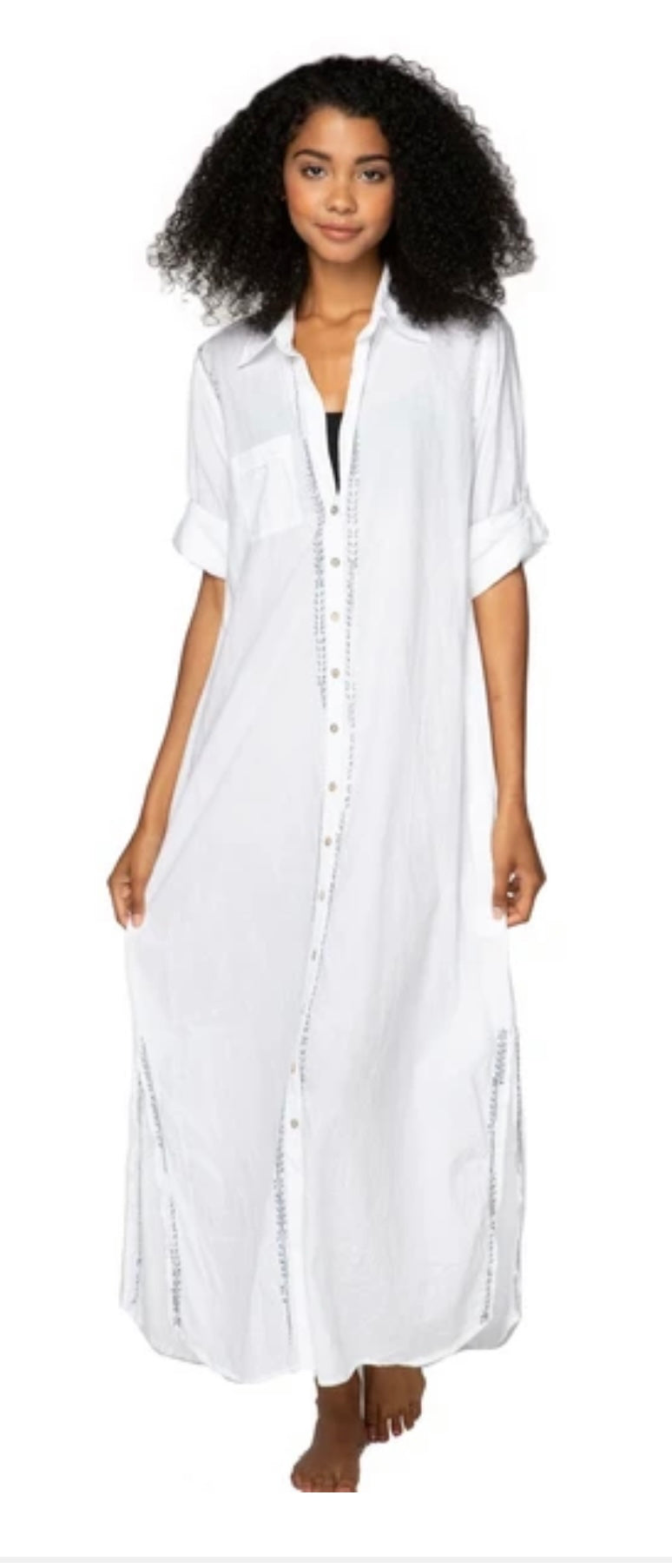white dress with rolled sleeves. the dress has buttons going down the length of the dress and a front pocket. Silver embroidery down the buttons and the slits on the side of the dress.