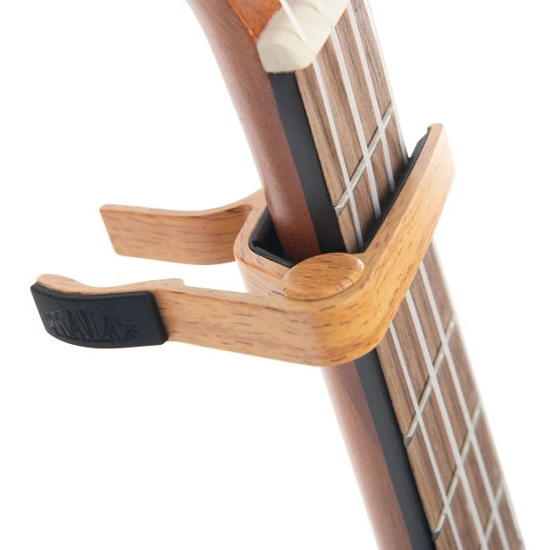 Bamboo capo diagonal display with white background on ukulele fret. 