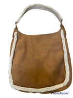 tan bag with white fleecy hand strap that. Decorated with white fleece at the seams